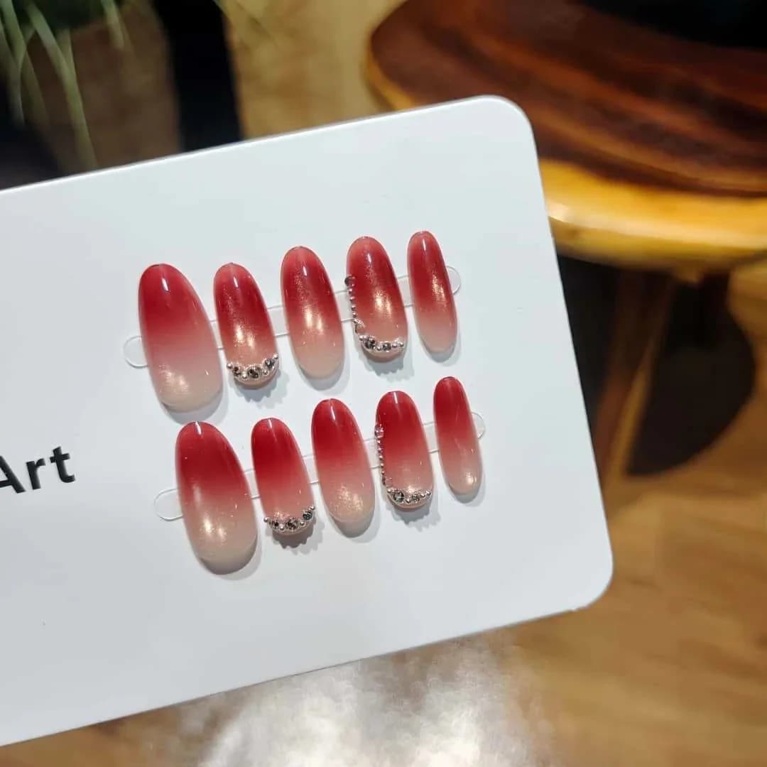Punased kassisilma efektiga kunstküüned rhinestones'ega, keskmise ovaalse kujuga