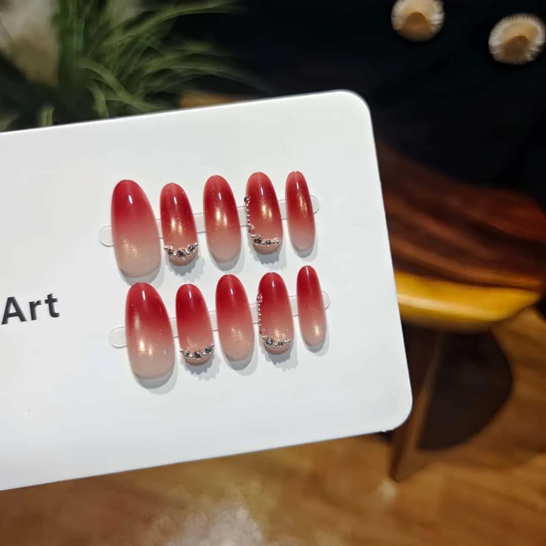 Punased kassisilma efektiga kunstküüned rhinestones'ega, keskmise ovaalse kujuga